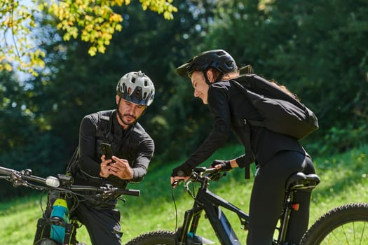 A sweet couple, equipped with bicycles and engrossed in coordinating their journey, checks their GPS mobile and watches while planning scenic routes in the park, seamlessly blending technology and outdoor adventure for a delightful cycling experience.