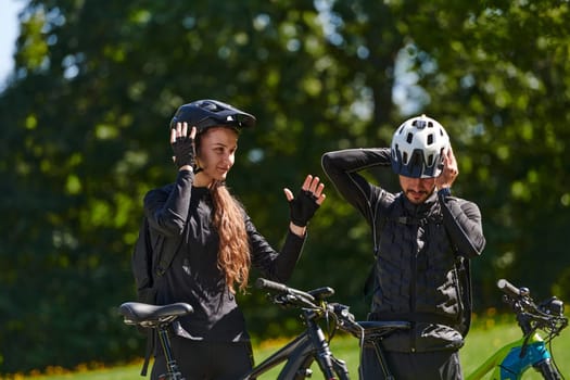 A sweet couple, equipped with bicycles and engrossed in coordinating their journey, checks their GPS mobile and watches while planning scenic routes in the park, seamlessly blending technology and outdoor adventure for a delightful cycling experience.