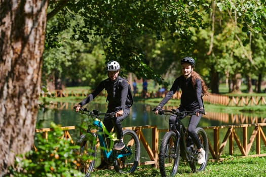 A blissful couple, adorned in professional cycling gear, enjoys a romantic bicycle ride through a park, surrounded by modern natural attractions, radiating love and happiness.