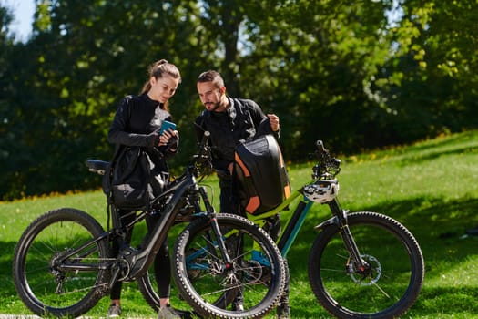 A sweet couple, equipped with bicycles and engrossed in coordinating their journey, checks their GPS mobile and watches while planning scenic routes in the park, seamlessly blending technology and outdoor adventure for a delightful cycling experience.