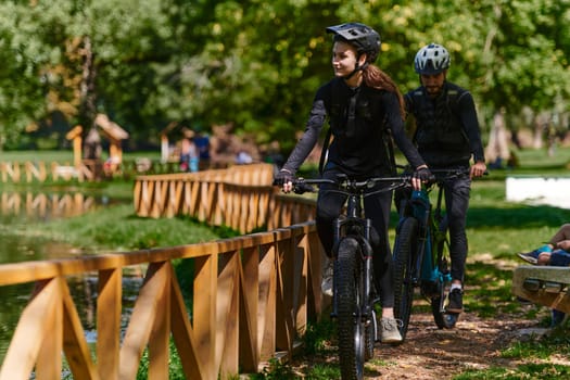 A blissful couple, adorned in professional cycling gear, enjoys a romantic bicycle ride through a park, surrounded by modern natural attractions, radiating love and happiness.