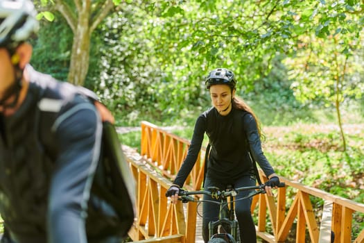 A blissful couple, adorned in professional cycling gear, enjoys a romantic bicycle ride through a park, surrounded by modern natural attractions, radiating love and happiness.