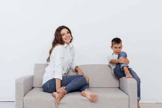 Mom and son sit on the sofa at home in a room