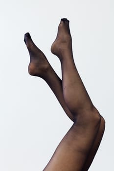 slender women's legs in black tights on a white background