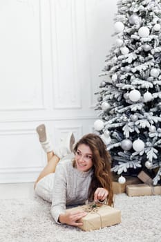 woman opens a gift at the Christmas tree with gifts new year