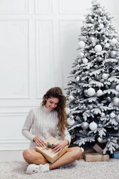 woman opens a gift at the Christmas tree with gifts new year