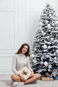 woman opens a gift at the Christmas tree with gifts new year