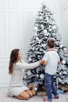 mom and son at the Christmas tree with new year gifts