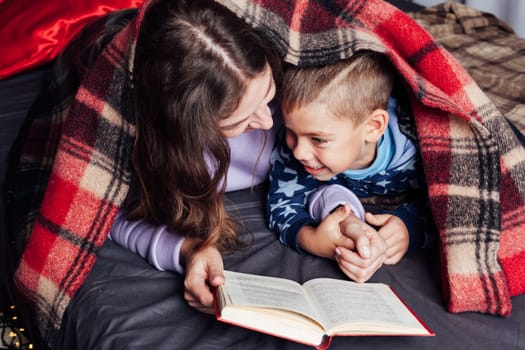 mother reads her son a book in bed before going to bed new year