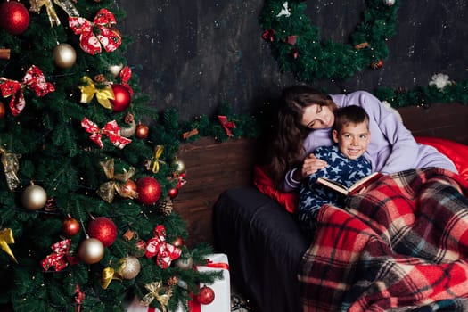 mother reads her son a book in bed before going to bed new year