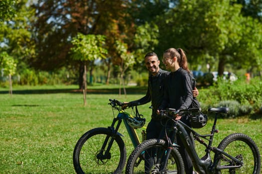 A blissful couple, adorned in professional cycling gear, enjoys a romantic bicycle ride through a park, surrounded by modern natural attractions, radiating love and happiness.