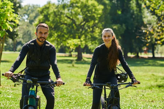 A blissful couple, adorned in professional cycling gear, enjoys a romantic bicycle ride through a park, surrounded by modern natural attractions, radiating love and happiness.