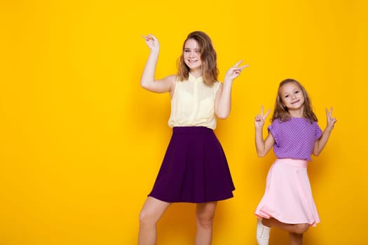 two girls in colored dresses laugh show fingers 2