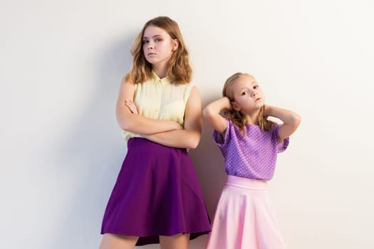 two sisters girls in colored dresses white walls 1