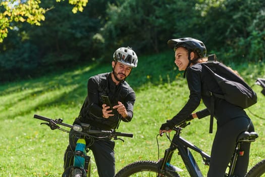 A sweet couple, equipped with bicycles and engrossed in coordinating their journey, checks their GPS mobile and watches while planning scenic routes in the park, seamlessly blending technology and outdoor adventure for a delightful cycling experience.