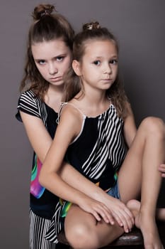 two girls sisters side by side on a grey background 1