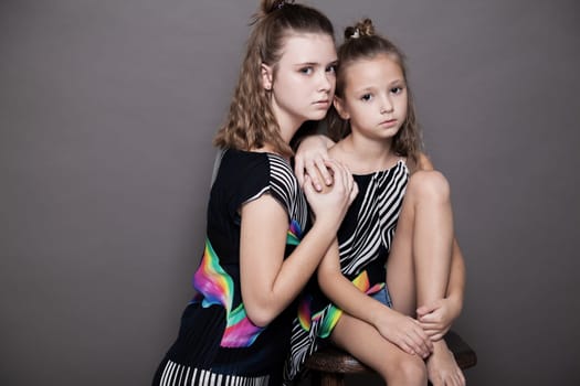 two girls sisters side by side on a grey background 1
