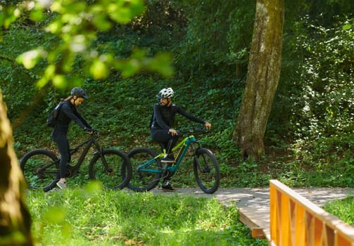 A blissful couple, adorned in professional cycling gear, enjoys a romantic bicycle ride through a park, surrounded by modern natural attractions, radiating love and happiness.