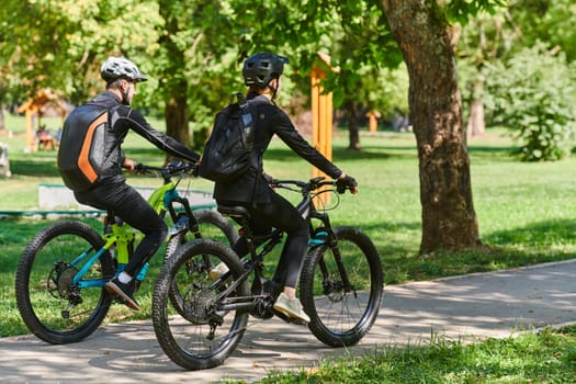 A blissful couple, adorned in professional cycling gear, enjoys a romantic bicycle ride through a park, surrounded by modern natural attractions, radiating love and happiness.
