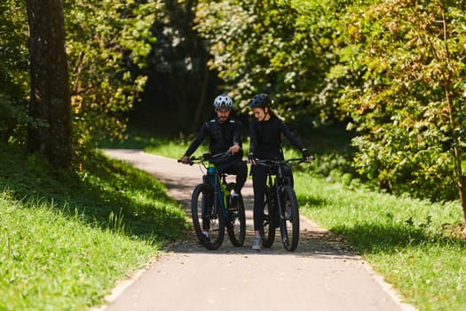 A blissful couple, adorned in professional cycling gear, enjoys a romantic bicycle ride through a park, surrounded by modern natural attractions, radiating love and happiness.