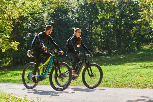 A blissful couple, adorned in professional cycling gear, enjoys a romantic bicycle ride through a park, surrounded by modern natural attractions, radiating love and happiness.