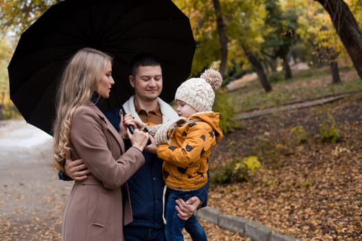 with his son's family in autumn in Park forest rain umbrella