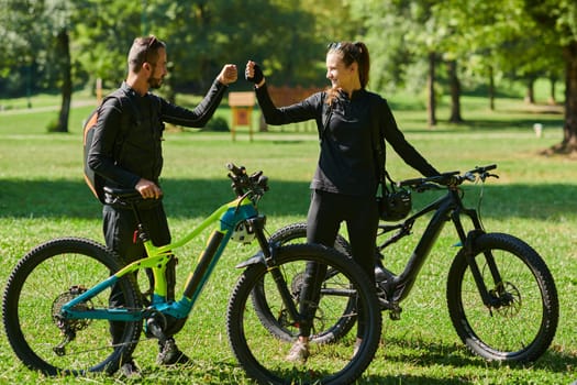 A sweet couple, adorned in cycling gear, rides their bicycles, their hands interlocked in a romantic embrace, capturing the essence of love, adventure, and joy on a sunlit path.