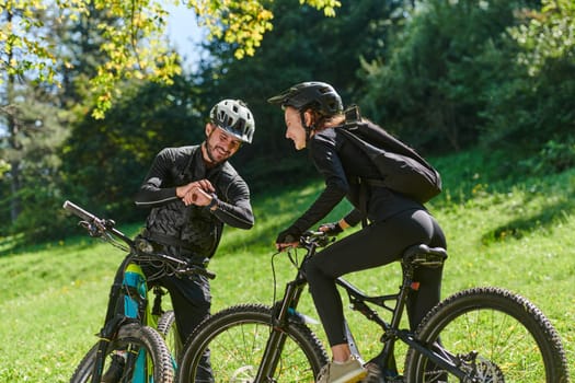 A sweet couple, equipped with bicycles and engrossed in coordinating their journey, checks their GPS mobile and watches while planning scenic routes in the park, seamlessly blending technology and outdoor adventure for a delightful cycling experience.