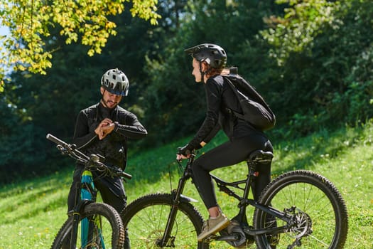 A sweet couple, equipped with bicycles and engrossed in coordinating their journey, checks their GPS mobile and watches while planning scenic routes in the park, seamlessly blending technology and outdoor adventure for a delightful cycling experience.