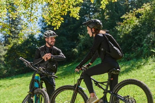 A sweet couple, equipped with bicycles and engrossed in coordinating their journey, checks their GPS mobile and watches while planning scenic routes in the park, seamlessly blending technology and outdoor adventure for a delightful cycling experience.