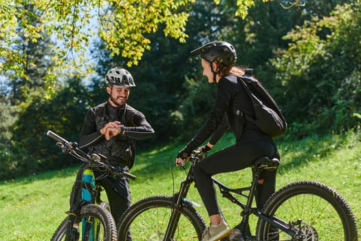 A sweet couple, equipped with bicycles and engrossed in coordinating their journey, checks their GPS mobile and watches while planning scenic routes in the park, seamlessly blending technology and outdoor adventure for a delightful cycling experience.