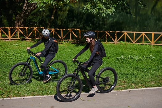 A blissful couple, adorned in professional cycling gear, enjoys a romantic bicycle ride through a park, surrounded by modern natural attractions, radiating love and happiness.