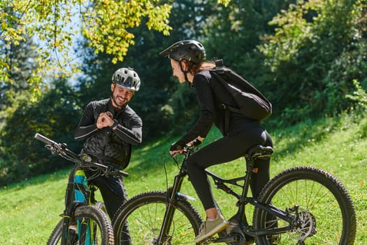 A sweet couple, equipped with bicycles and engrossed in coordinating their journey, checks their GPS mobile and watches while planning scenic routes in the park, seamlessly blending technology and outdoor adventure for a delightful cycling experience.