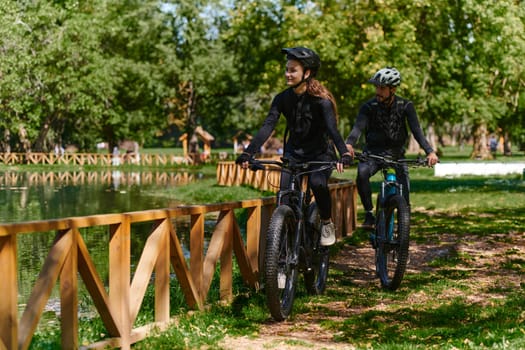 A blissful couple, adorned in professional cycling gear, enjoys a romantic bicycle ride through a park, surrounded by modern natural attractions, radiating love and happiness.