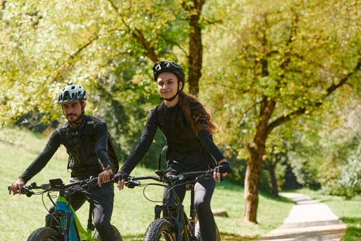 A blissful couple, adorned in professional cycling gear, enjoys a romantic bicycle ride through a park, surrounded by modern natural attractions, radiating love and happiness.