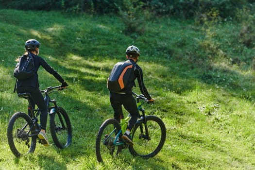 A blissful couple, adorned in professional cycling gear, enjoys a romantic bicycle ride through a park, surrounded by modern natural attractions, radiating love and happiness.