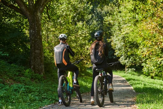 A blissful couple, adorned in professional cycling gear, enjoys a romantic bicycle ride through a park, surrounded by modern natural attractions, radiating love and happiness.