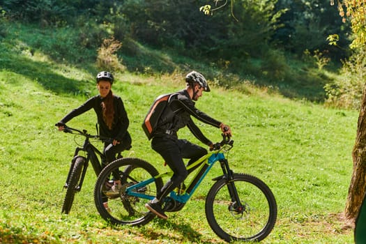 A blissful couple, adorned in professional cycling gear, enjoys a romantic bicycle ride through a park, surrounded by modern natural attractions, radiating love and happiness.