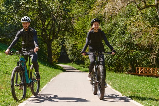 A blissful couple, adorned in professional cycling gear, enjoys a romantic bicycle ride through a park, surrounded by modern natural attractions, radiating love and happiness.