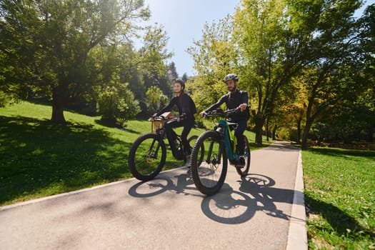 A blissful couple, adorned in professional cycling gear, enjoys a romantic bicycle ride through a park, surrounded by modern natural attractions, radiating love and happiness.