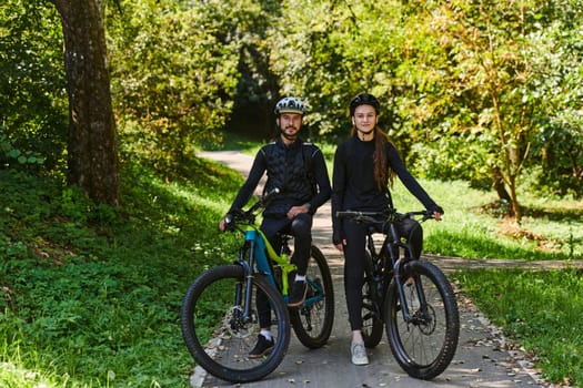 A blissful couple, adorned in professional cycling gear, enjoys a romantic bicycle ride through a park, surrounded by modern natural attractions, radiating love and happiness.