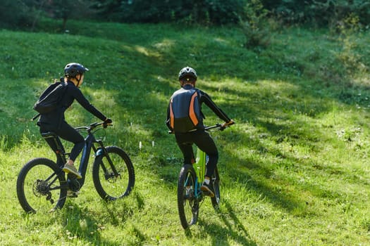 A blissful couple, adorned in professional cycling gear, enjoys a romantic bicycle ride through a park, surrounded by modern natural attractions, radiating love and happiness.