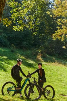 A sweet couple, equipped with bicycles and engrossed in coordinating their journey, checks their GPS mobile and watches while planning scenic routes in the park, seamlessly blending technology and outdoor adventure for a delightful cycling experience.