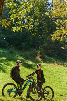 A sweet couple, equipped with bicycles and engrossed in coordinating their journey, checks their GPS mobile and watches while planning scenic routes in the park, seamlessly blending technology and outdoor adventure for a delightful cycling experience.