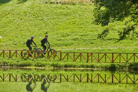 A blissful couple, adorned in professional cycling gear, enjoys a romantic bicycle ride through a park, surrounded by modern natural attractions, radiating love and happiness.