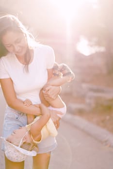 Smiling mom holding little girl upside down in bright sunlight. High quality photo