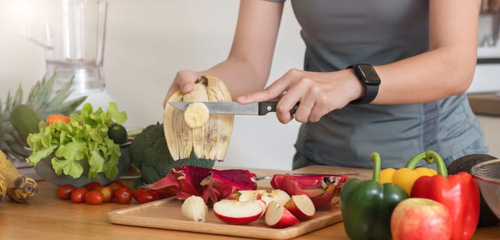 Healthy Asian woman takes care of her health by eating vegetable and fruit salad, adding vitamins in the kitchen..