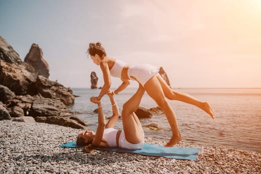 Woman sea yoga. Back view of free calm happy satisfied woman with long hair standing on top rock with yoga position against of sky by the sea. Healthy lifestyle outdoors in nature, fitness concept.