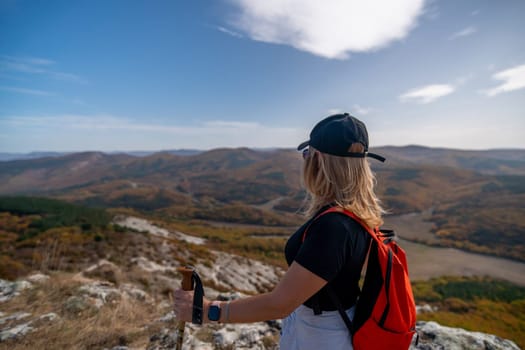 woman on mountain peak looking in beautiful mountain valley in autumn. Landscape with sporty young woman, blu sky in fall. Hiking. Nature.