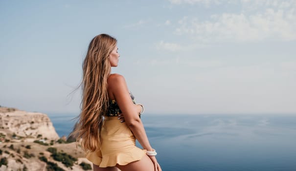 Woman travel sea. Happy tourist taking picture outdoors for memories. Woman traveler looks at the edge of the cliff on the sea bay of mountains, sharing travel adventure journey.